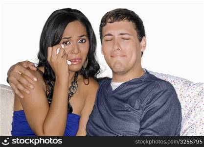 Young man and a teenage girl watching television and crying