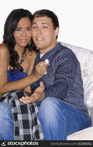 Young man and a teenage girl watching television and crying