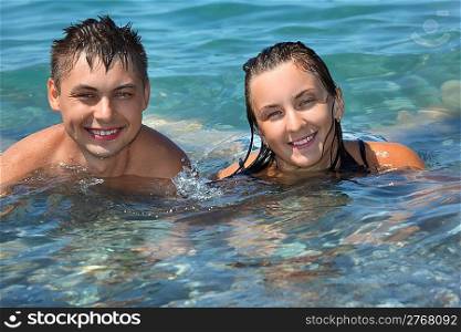 young man and beautiful woman bathe in sea