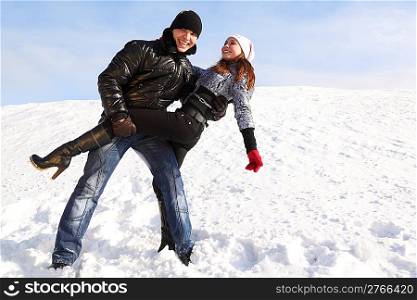 young man and girl dance on snowy area and smiling, man looking at camera