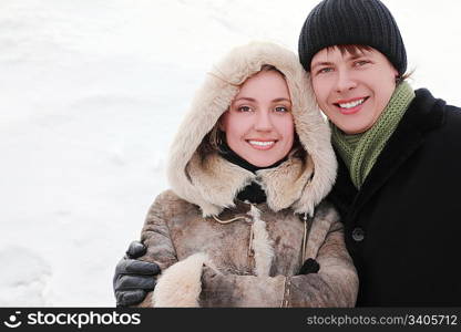 young man and girl in warm dress smiling, embracing and looking at camera, half body, winter day