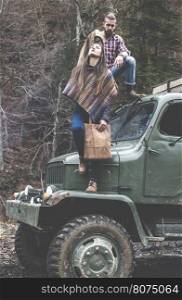 Young man and girl on truck with logs in the forest