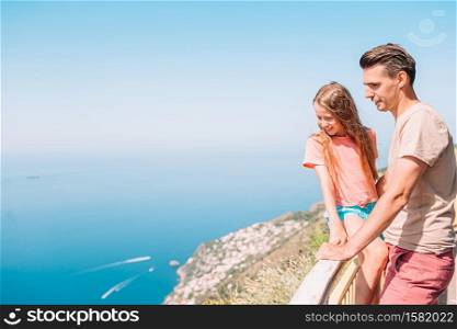 Young man and little daughter on the background of Amalfi Coast in Italy. Family of dad and kid on summer vacation on the background of Amalfi Coast, Italy