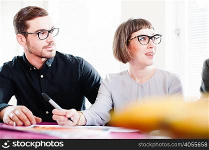 Young man and mid adult woman wearing glasses in meeting
