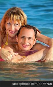 young man and nice women lying on an inflatable mattress in pool, woman lying astride man