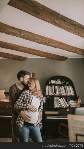 Young man and pregnant woman hugging in the room at home