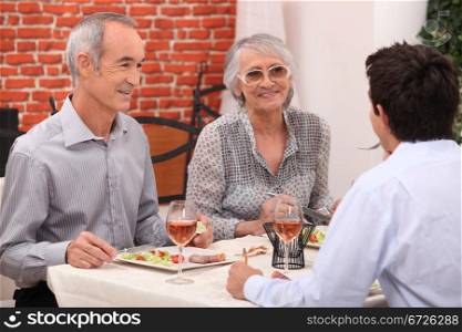 Young man and senior couple having a dinner in a restaurant