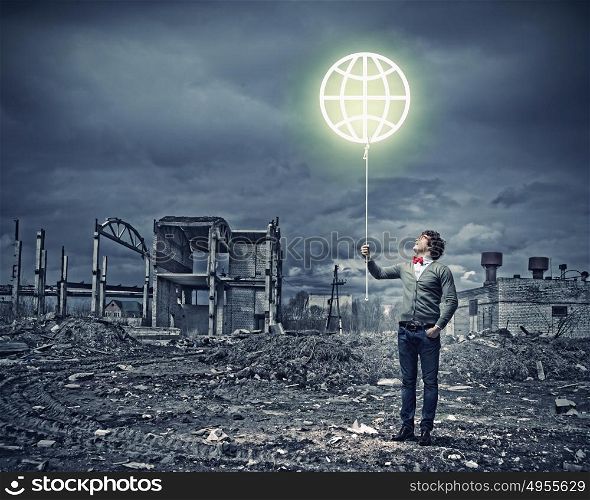 Young man and the symbol of our planet. Young man and the symbol of our planet against polluted and ruined landscape