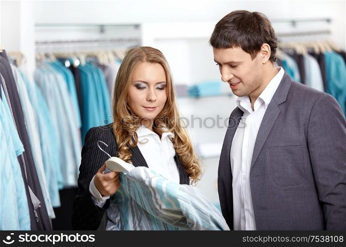 Young man and the woman consider a shirt in shop