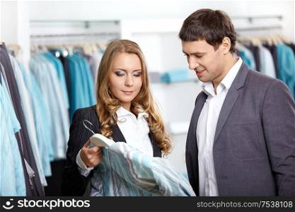 Young man and the woman consider a shirt in shop