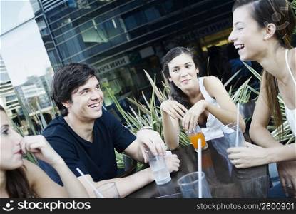 Young man and three young women smiling together in a restaurant