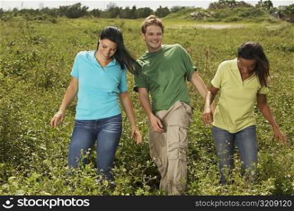 Young man and two young women walking in a field