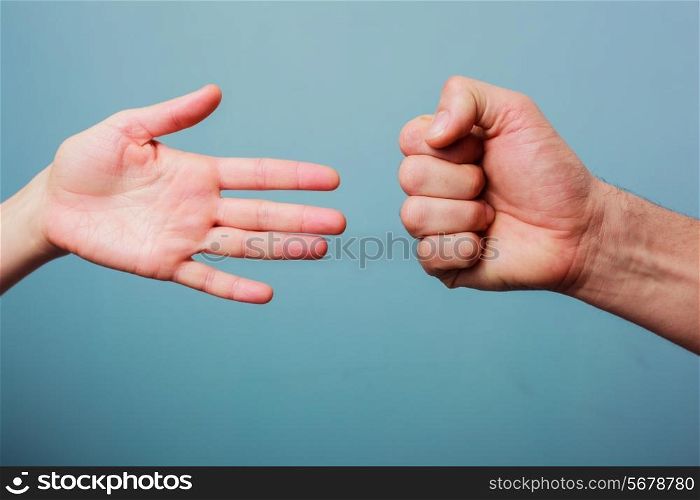 Young man and woman are playing rock paper scissors