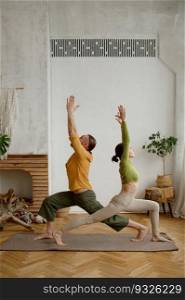 Young man and woman couple practicing yoga together standing in triangle pose. Healthy lifestyle and sport daily routine concept. Young man and woman couple practicing yoga together standing in triangle pose