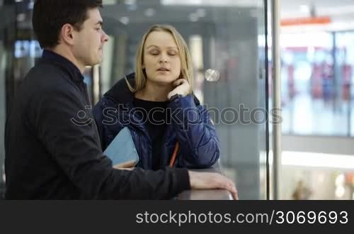 Young man and woman discussing something in shopping center. Woman trying to explain her point of view with gestures