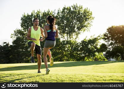 Young man and woman doing running on spot training in park