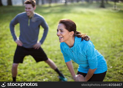 Young man and woman doing warm up training in park