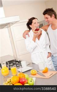 Young man and woman eating toast for breakfast in modern kitchen