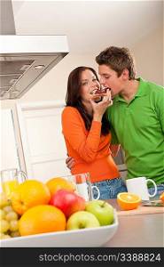 Young man and woman eating toast together in the kitchen