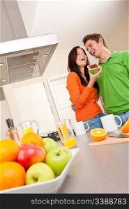 Young man and woman eating toast with marmalade together in the kitchen