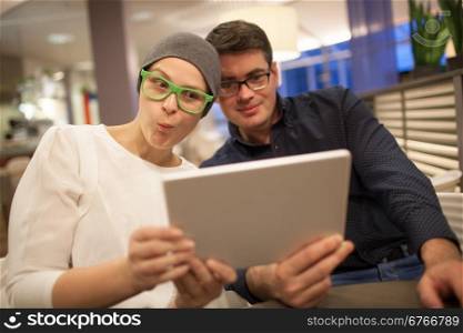 Young man and woman in glasses wriggle while making selfie sitting in the restaurant