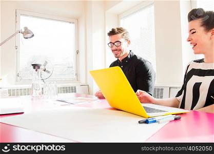 Young man and woman in office using laptop