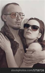 Young man and woman in sunglasses on white background