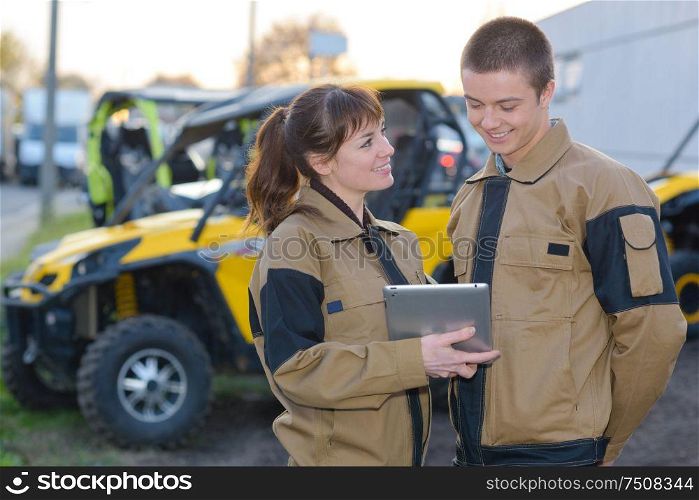 Young man and woman in uniform outdoors with tablet