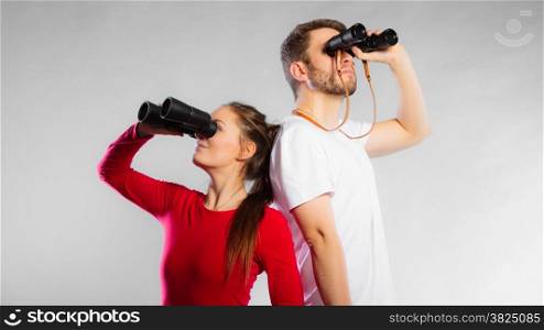 Young man and woman lifeguards on duty or tourist couple looking through binocular studio shot on gray
