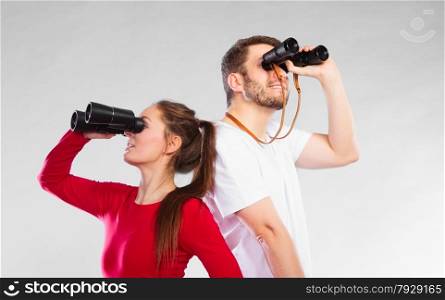 Young man and woman lifeguards on duty or tourist couple looking through binocular studio shot on gray