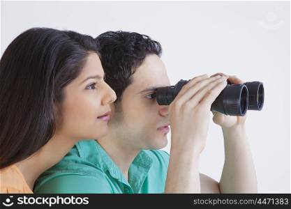 Young man and woman looking through binoculars