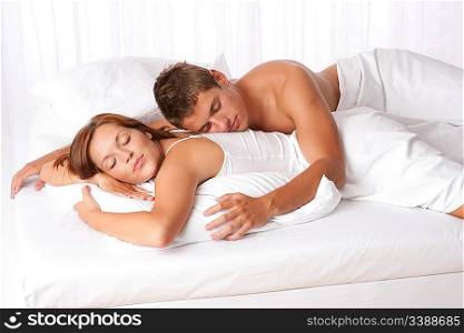 Young man and woman lying down in white bed and sleeping
