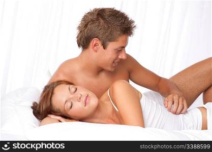 Young man and woman lying down in white bed and woman sleeping