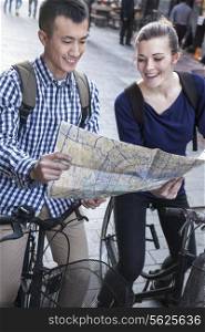 Young man and woman on bicycles, looking at map.