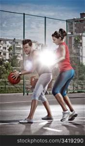 Young man and woman playing basketball on the playground