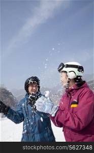 Young Man and Woman Playing in the Snow in Ski Resort