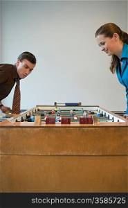 Young man and woman playing table football in games room