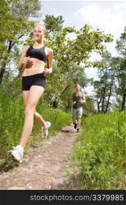 Young man and woman running on a pathway