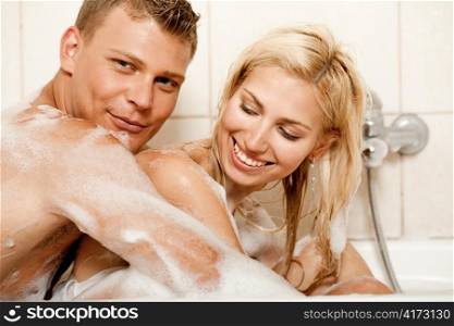 Young man and woman sharing bath and smiling looking at camera