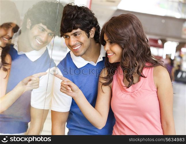 Young man and woman smiling while window shopping