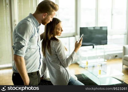 Young man and woman standing embraced in the room and using mobile phone