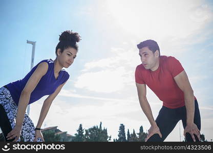 Young man and woman training, taking a break at sport facility