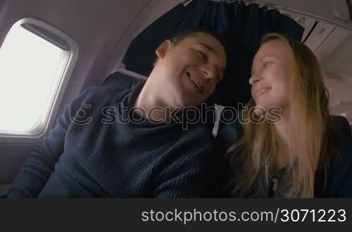 Young man and woman traveling by plane. They are happy and showing their tender and romantic feelings