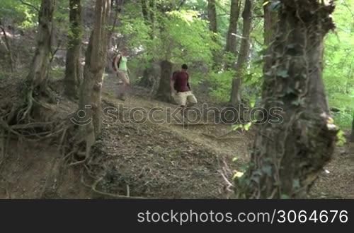 Young man and woman walking in woods and crossing river