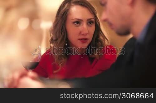 Young man and woman with a glass of wine talking in the cafe or restaurant