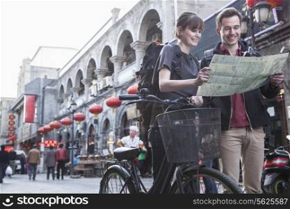Young man and woman with bicycle and map.