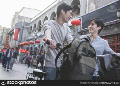 Young man and woman with bicycles and backpacks.