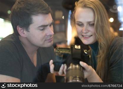 Young man and woman with digital camera. They looking through the photos and searching the best shots. Woman smiling