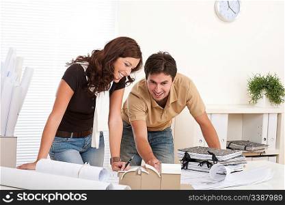 Young man and woman working at architect office with architectural model