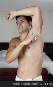 Young man applying deodorant under his armpit